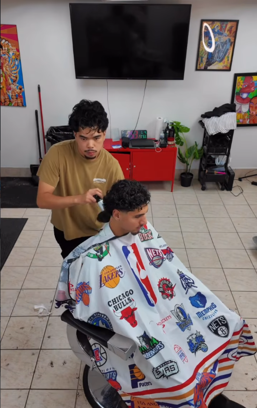 Jordan cutting a client's curly hair at his station